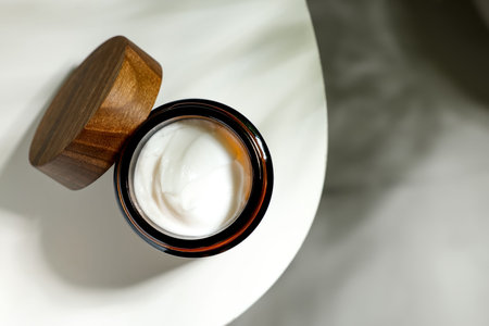 Open jar of cosmetic cream on white table, top view. Space for textの写真素材