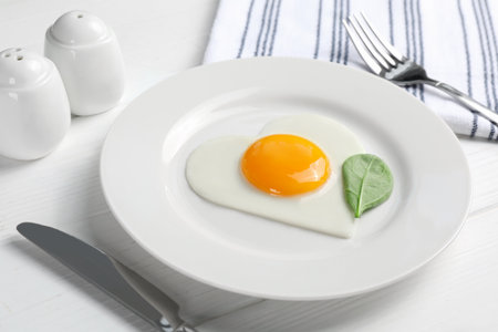 Romantic breakfast with heart shaped fried egg on white wooden table, closeupの写真素材