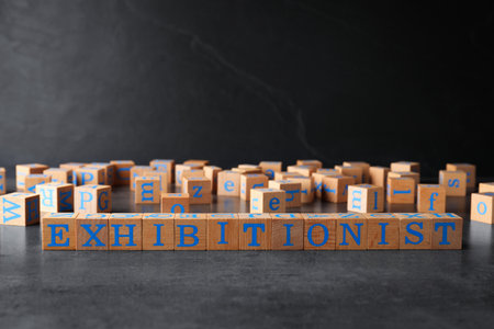 Word EXHIBITIONIST made with wooden cubes on gray tableの写真素材
