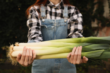 Woman holding fresh raw leeks outdoors, closeupの写真素材