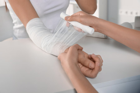 Doctor applying bandage onto patient's arm in hospital, closeupの写真素材