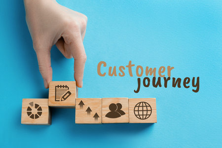 Woman arranging wooden cubes with different images on light blue background, top view. customer journey conceptの写真素材