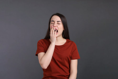 Portrait of bored young woman on dark gray background. Personality conceptの写真素材