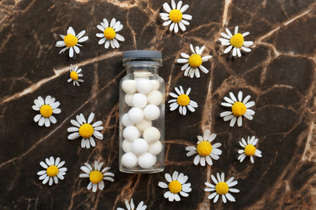 Bottle of homeopathic remedy and beautiful chamomiles on textured background, flat layの写真素材