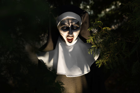 Portrait of scary devilish nun near tree outdoors. halloween party lookの写真素材