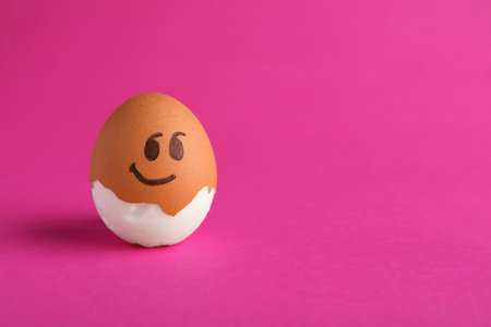 Egg with drawn face on pink background, space for text. exhibitionist concept