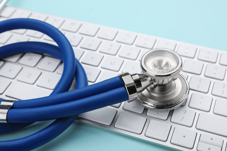 Computer keyboard with stethoscope on turquoise background, closeupの写真素材