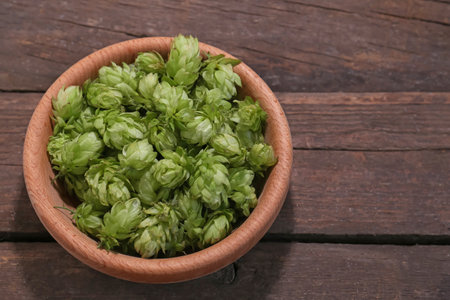 Bowl of fresh green hops on wooden table, above view. Space for textの写真素材