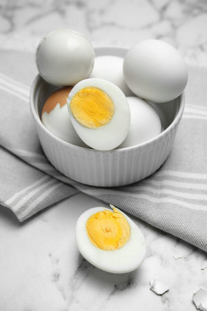Bowl with hard boiled eggs on white marble tableの写真素材