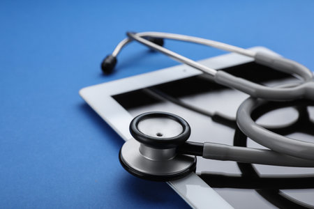 Computer tablet with stethoscope on blue background, closeupの写真素材