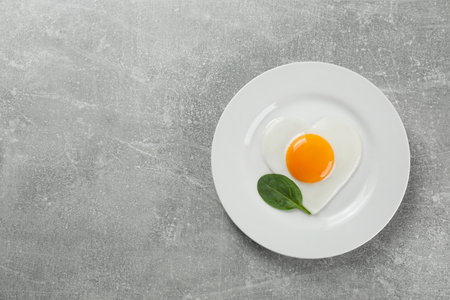 Romantic breakfast with fried egg on light gray table, top view. Space for textの写真素材
