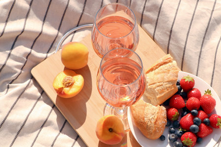 Glasses of delicious rose wine and food on white picnic blanketの写真素材