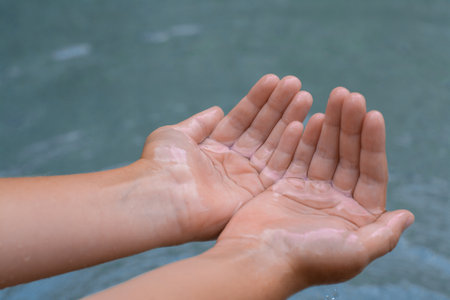Kid holding water in hands above sea outdoors, closeupの写真素材