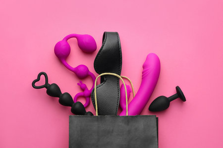 Shopping bag with different sex toys on pink background, flat layの写真素材