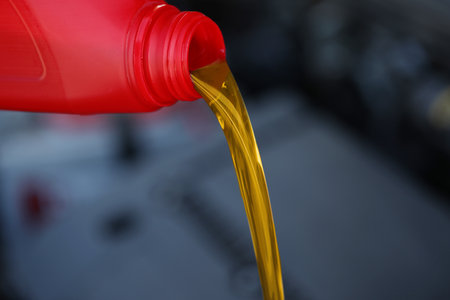 Pouring motor oil from red container against blurred background, closeupの写真素材