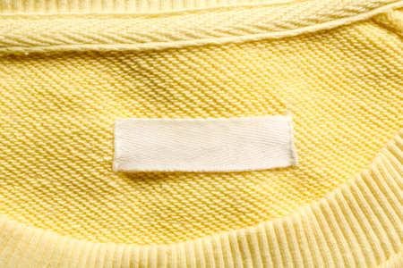 Blank clothing label on yellow sweater, top view