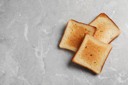 Slices of delicious toasted bread on gray marble table, top view. Space for textの写真素材