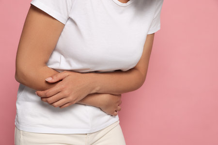 Young woman suffering from menstrual pain on pink background, closeup. Space for textの写真素材