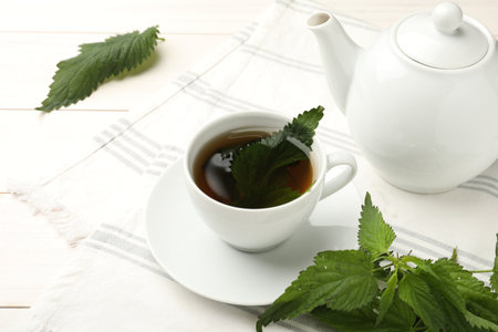 Aromatic nettle tea and green leaves on white wooden tableの写真素材