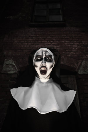 Portrait of scary devilish nun outdoors. halloween party lookの写真素材