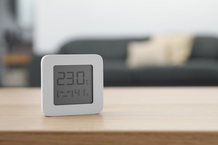 Digital hygrometer with thermometer on wooden table indoors. Space for text