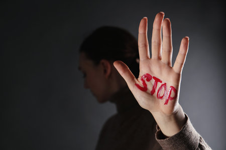 Woman with word Stop written on hand against black background, closeup and space for text. domestic violence conceptの写真素材