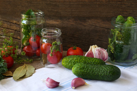 Glass jars, fresh vegetables and herbs on wooden table. pickling recipeの写真素材