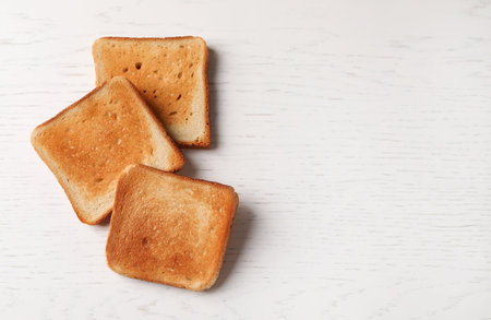Slices of delicious toasted bread on white wooden table, top view. Space for textの写真素材