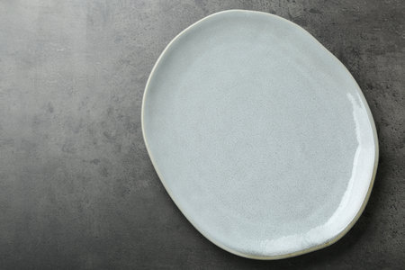 Empty ceramic plate on gray table, top view. Space for text