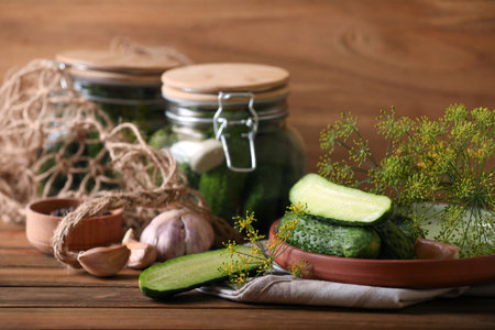 Fresh cucumbers and other ingredients prepared for canning on wooden tableの写真素材