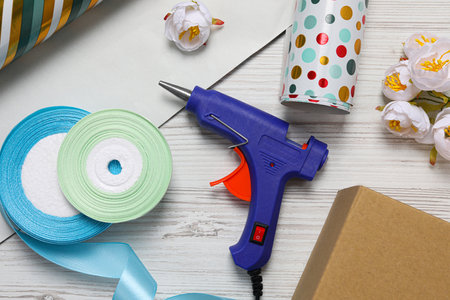 Hot glue gun and handicraft materials on white wooden table, flat layの写真素材