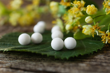 Homeopathic remedy and linden flowers on wooden table, closeupの写真素材