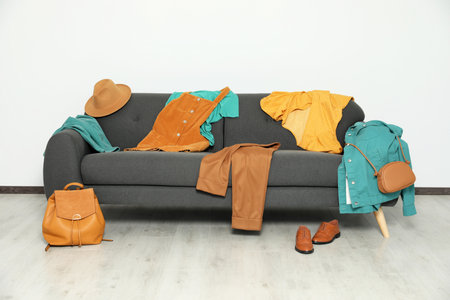 Messy pile of clothes on sofa and shoes in living roomの写真素材