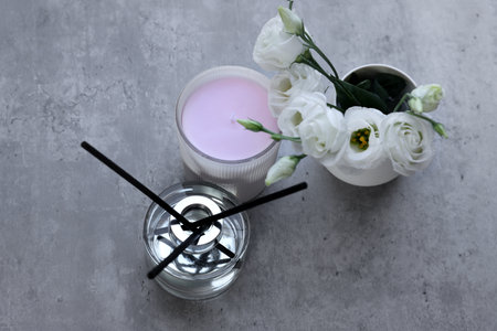 Reed diffuser, scented candle and eustoma flowers on gray marble table, flat lay
