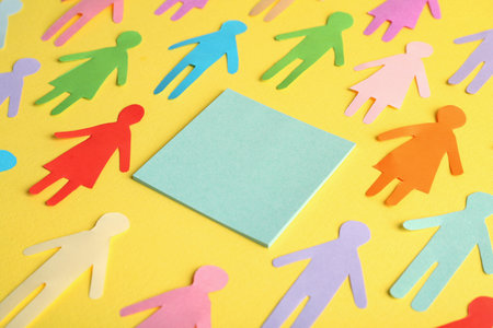 Many different paper human figures around blank card on yellow background, space for text. Diversity and inclusion conceptの写真素材