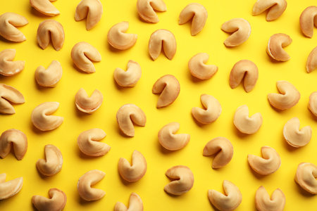 Many tasty fortune cookies with predictions on yellow background, flat layの写真素材