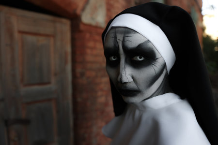 Portrait of scary devilish nun outdoors, space for text. halloween party lookの写真素材