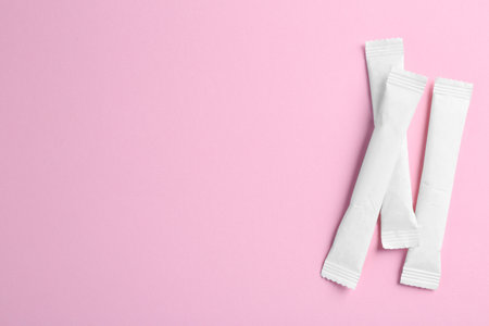 White sticks of sugar on pink background, flat lay. Space for textの写真素材