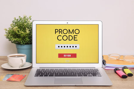 Laptop with activated promo code on wooden table indoorsの写真素材