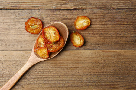 Spoon and cut dried kumquat fruits on wooden table, flat lay. Space for textの写真素材
