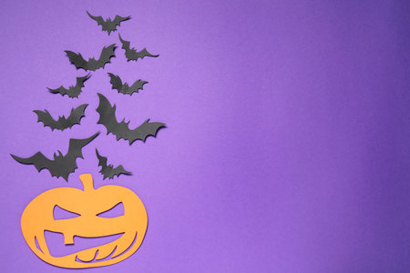 Flat lay composition with paper bats and pumpkin on purple background, space for text. halloween decorの写真素材