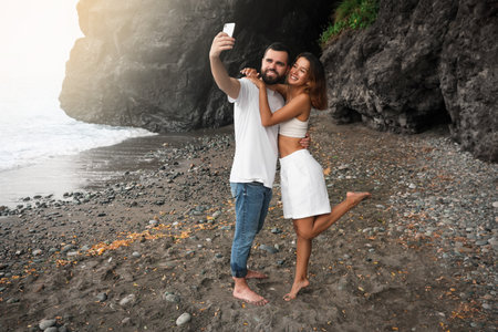 Happy young couple taking selfie on beach near sea. Space for textの写真素材