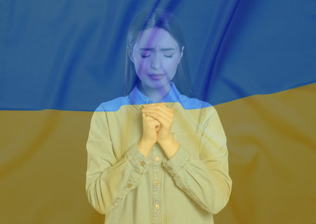 Double exposure of national flag and woman praying. Stop war in Ukraineの写真素材