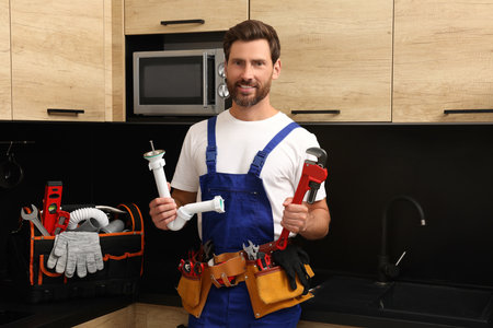 Professional plumber with corrugated pipe and wrench in kitchenの写真素材