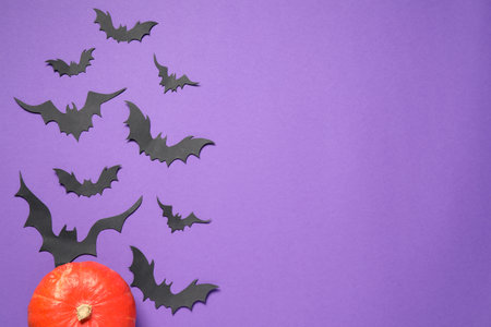 Flat lay composition with pumpkin and paper bats on purple background, space for text. halloween decorの写真素材
