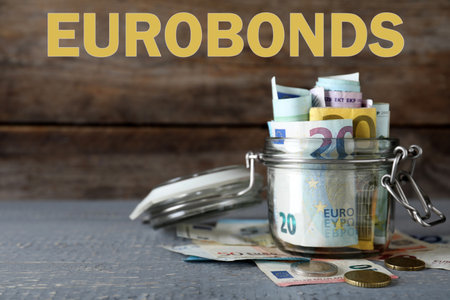 Eurobond concept. Glass jar full of money on wooden tableの写真素材