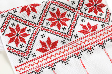 Traditional Ukrainian embroidery on white canvas as background, closeup. national handicraft