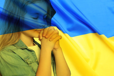 Double exposure of national flag and little girl praying. Stop war in Ukraineの写真素材