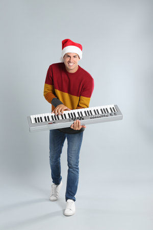 Man in Santa hat playing synthesizer on light gray background. christmas musicの写真素材