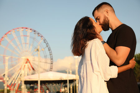 Happy young couple kissing in amusement parkの写真素材